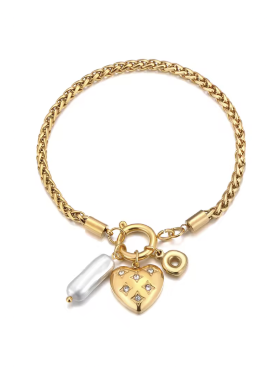 Złota bransoletka z zawieszkami: serce, podłużna imitacja perły i kulka. Białe tło